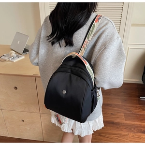 Dettaglio dello zaino in nylon nero con spallacci ricamati a motivi geometrici colorati