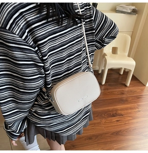 Gros plan détaillé d'un sac caméra en cuir grainé beige avec des finitions argentées