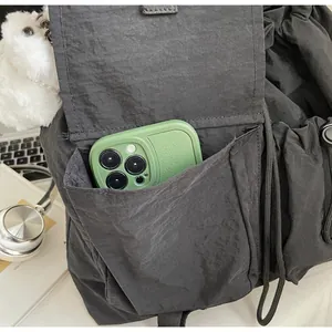 Close-up of a side pocket on a black nylon drawstring bag holding a green smartphone