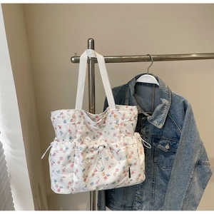 Detail of floral tote bag with drawstring side pockets and white woven shoulder straps