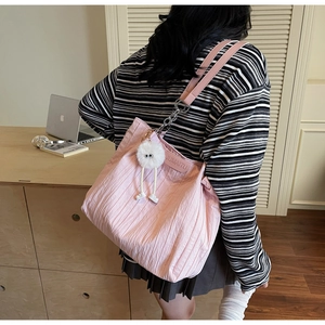 Dettaglio della trama della borsa tote rosa pieghettata con charm a mostro di peluche bianco