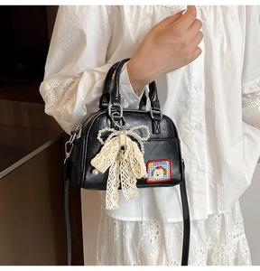 Détail du sac bowling noir avec nœud en dentelle perlée et patch de chiot mignon