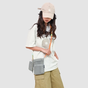 Detail of grey mesh crossbody bag with vibrant orange rope strap and side zip pouch