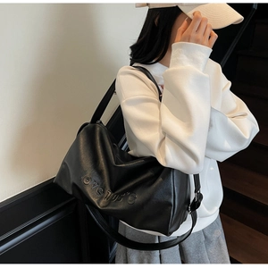 Detail of black PU leather tote bag featuring a love 105 degree embossed slogan design