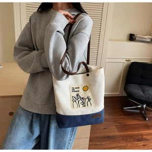 Detail of color-block canvas tote bag with adjustable straps and artistic text print