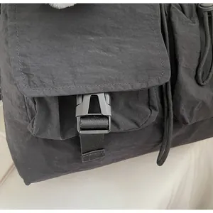 Close-up of the durable black plastic buckle and textured nylon fabric on the crossbody bag