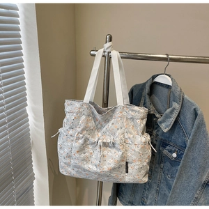 Close-up of floral lace tote bag with white handles and side drawstring pocket detail