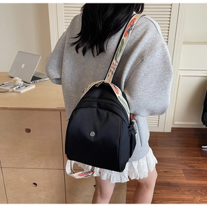 Dettaglio dello zaino nero in nylon con tracolla jacquard colorata indossato in ufficio