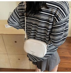 Gros plan du sac bandoulière beige en cuir grainé avec des finitions en métal argenté