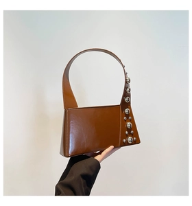 Detail of a brown glossy leather shoulder bag with decorative silver spherical rivets
