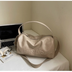 Detail of beige Boston bag with love 105 embossed text on desk with laptop and headphones