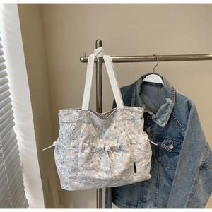 Detailed close-up of gray lace tote bag featuring orange floral patterns and white straps