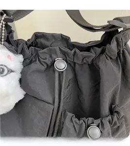 Detail view of black nylon crossbody bag featuring a drawstring closure and white plush bunny