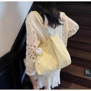Dettaglio della borsa tote plissettata giallo chiaro con catena e ciondolo a pompon