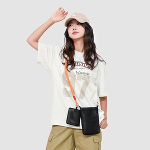 Mesh crossbody phone bag in black with vibrant orange rope strap shown on a casual model