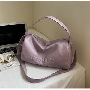 Close-up of purple leather tote bag with embossed letters and adjustable strap