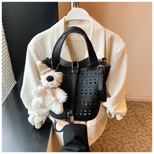Détail d'un sac seau noir ajouré en cuir grainé avec un petit pendentif d'ours