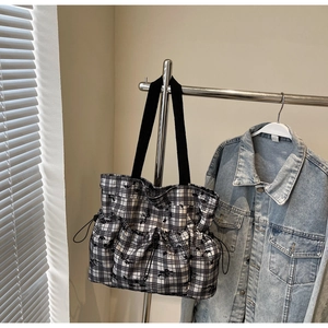 Detail view of a black and white checkered canvas tote bag with side drawstring pockets