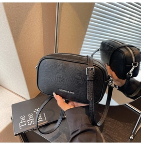 Détail du cuir grainé noir et de la fermeture éclair argentée sur ce sac à bandoulière