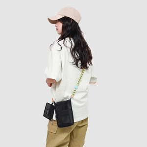 Detail of black mesh crossbody bag with sporty bicolor rope strap on a model