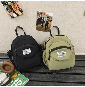 Detail of small nylon crossbody bags in black and olive green on a minimalist bench