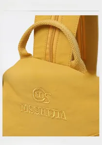 Detail view of the yellow backpack featuring sturdy top handle and MISSI JIA embroidery