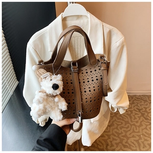 Détail du sac seau en cuir marron avec motifs découpés au laser et charmant porte-clés