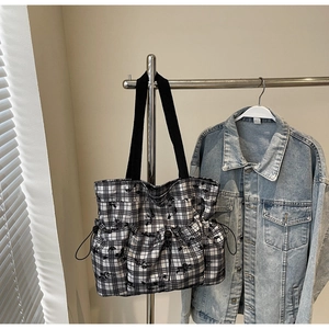 Detail view of checkered tote bag featuring cartoon prints and side drawstring pockets