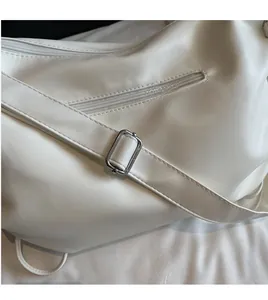 Vue détaillée du sac cabas blanc avec bandoulière réglable et boucle en métal argenté brillant