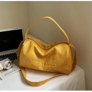 Detailed macro view of yellow PU leather cylinder bag with love 105 embossed text and zipper
