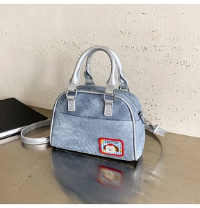 Détail du sac bowling en denim bleu avec anses argentées et écusson chien mignon