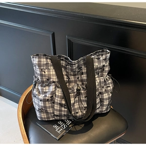 Close-up of black and white checkered tote bag with drawstring and canvas texture