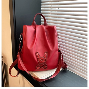 Detail of red nylon backpack showing sequined rabbit design and side pocket