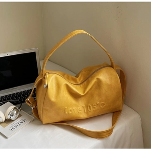 Close-up of bright yellow Boston bag with love 105°c embossed text and silver hardware