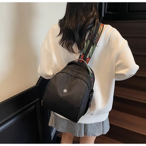 Dettaglio zaino in nylon nero con tracolla jacquard etnica colorata indossato da modella