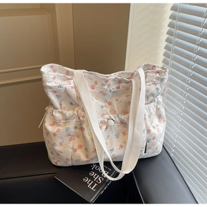 Detailed close-up of a floral tote bag with lace texture and side drawstring on a bench