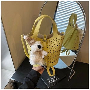Gros plan sur un sac seau jaune ajouré avec un pendentif chiot en peluche sur fond noir