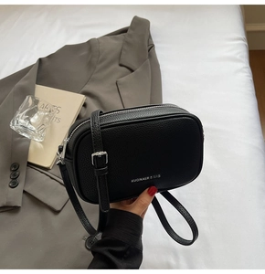 Détail d'un sac bandoulière noir en cuir grainé avec fermeture éclair argentée élégante