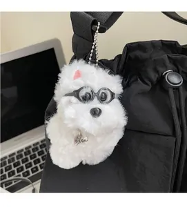 Detail of white plush dog bag charm with glasses and silver bone tag on a black bag