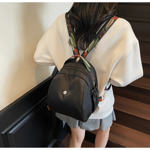 Dettaglio dello zaino in nylon nero con tracolla colorata ricamata in stile etnico