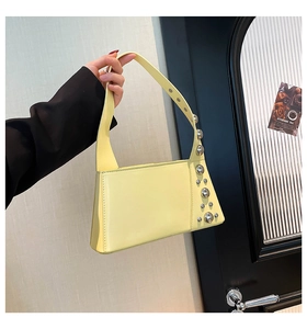 Detail view of cream shoulder bag with silver rivet studs and a trapezoid structure