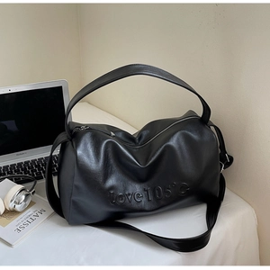 Detail of black faux leather tote bag with love 105°C embossed text and soft texture