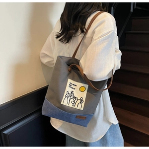 Close-up of canvas tote bag showing the side view and the brown leather shoulder straps