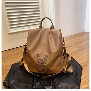 Detail of caramel nylon backpack with rabbit embroidery on high-quality fabric surface