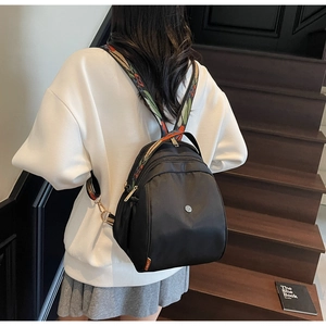 Dettaglio mini zaino in nylon nero con ampia tracolla a motivi colorati e dettagli oro