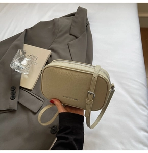 Gros plan du sac bandoulière beige en cuir grainé avec fermeture éclair argentée