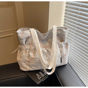Detail of white lace floral tote bag featuring orange flowers and drawstring closure