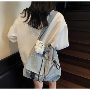 Detailed back view of a light blue drawstring crossbody bag with a plush bear charm