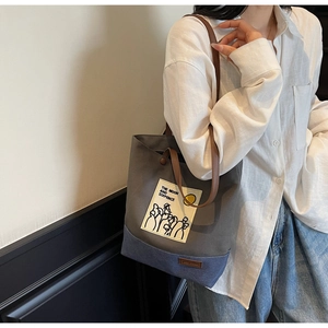 Detail of grey and blue canvas tote bag with leather handles and moon engraving