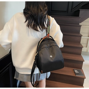 Dettaglio mini zaino in nylon nero con tracolla stampata a colori e logo in metallo